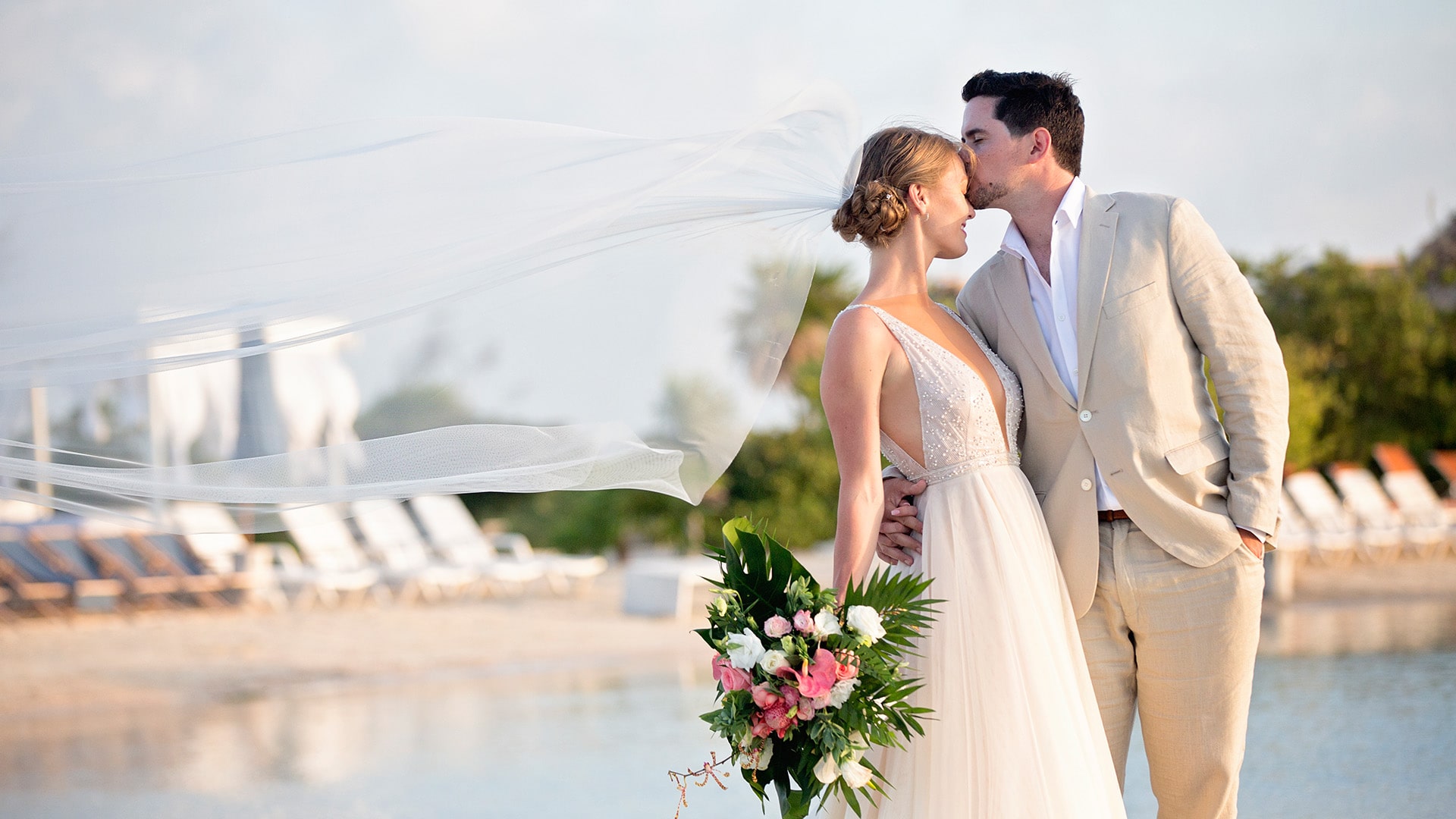 Man & woman kissing on beach at Mahogany Bay Resort